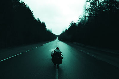 Man riding motorcycle on street against sky