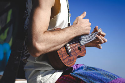 Midsection of man playing guitar