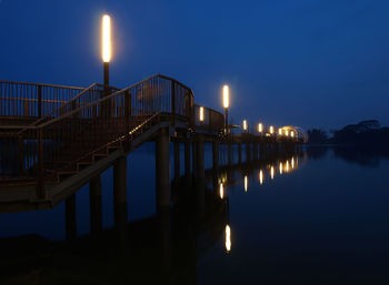 Illuminated bridge over river against sky at night