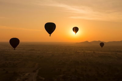 Four hot air balloons including one over rising sun at old bagan, myanmar