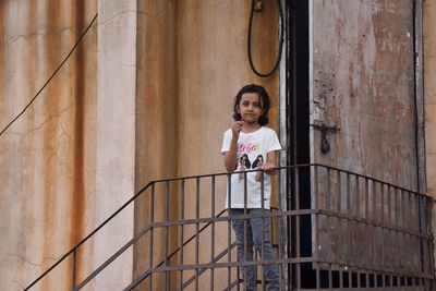 Portrait of a girl standing against railing