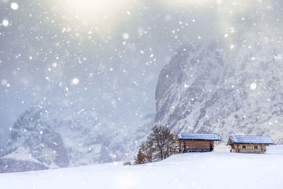 Cottages on snowcapped mountain against cloudy sky