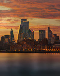 Illuminated buildings in city against sky during sunset