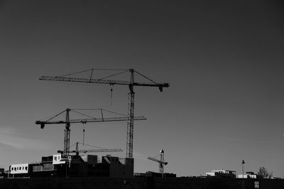 Low angle view of cranes at construction site against sky