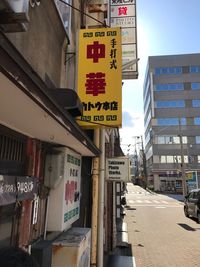 Road sign in city against sky