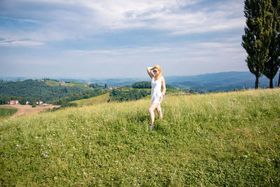 Woman with arms raised on field against sky