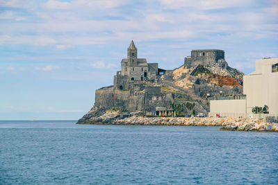 Building on cliff by sea against sky