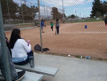 Rear view of people playing on chainlink fence