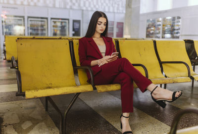 Woman sitting on in a waiting room with a phone in her hands