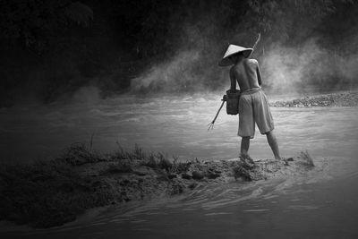 Rear view of man standing in river