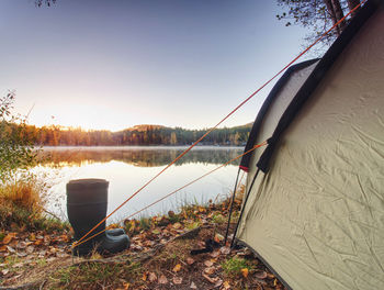 Green camping tent on the lake bank in early morning. daybreak sun touch against forest hill