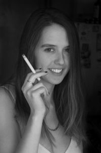 Close-up of smiling young woman holding cigarette