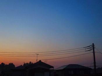 Low angle view of silhouette electricity pylon against clear sky