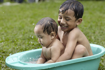 Close-up of siblings playing in bathtub in yard