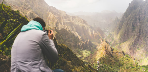 Rear view of man photographing while standing on mountain