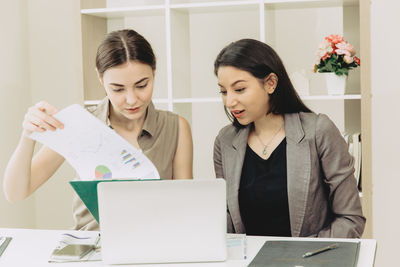 Young woman using smart phone in laptop