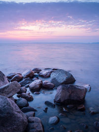 Rocks at sea shore against sky during sunset