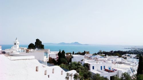 High angle view of townscape by sea against clear sky