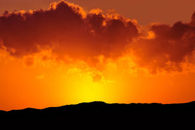 Scenic view of dramatic sky over silhouette landscape