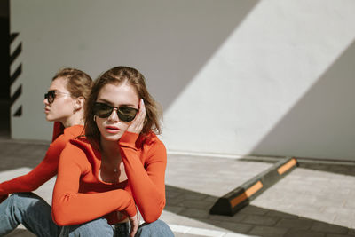 Portrait of two young girls in sunglasses and identical clothes posing in urban area. copy space.
