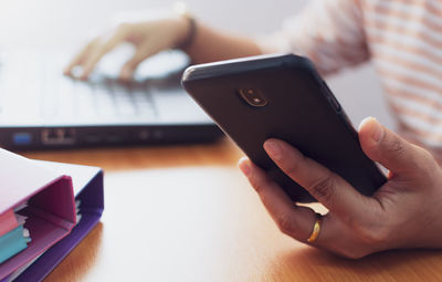 Close-up of hand using mobile phone on table