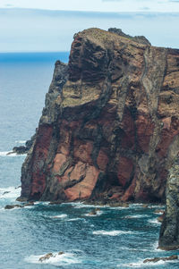 Rock formation on sea shore against sky