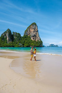 Rear view of woman standing at beach against sky