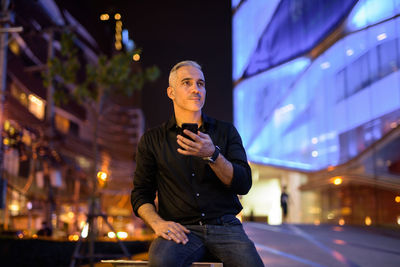 Full length of man standing on illuminated city at night