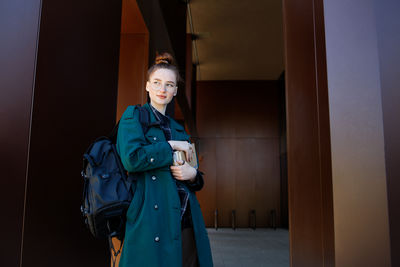 Young woman standing against wall