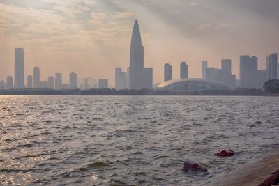 View of buildings in sea against cloudy sky