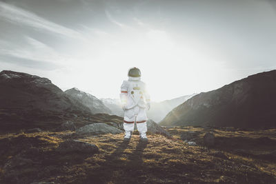 Astronaut standing on land against mountain