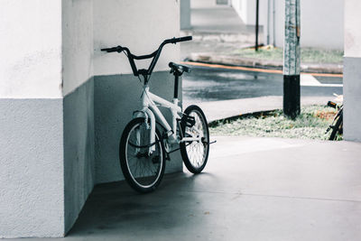 Bicycle on sidewalk against wall