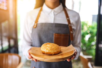 A waitress holding and serving a piece of homemade donut in wooden tray