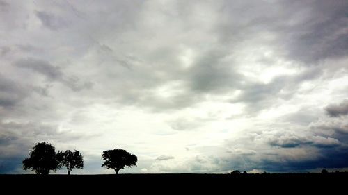 Low angle view of silhouette trees against cloudy sky