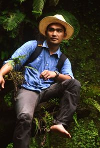 Young man sitting against plants