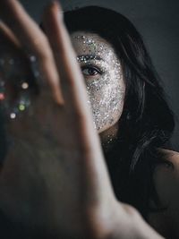 Close-up portrait of young woman with glitter on face
