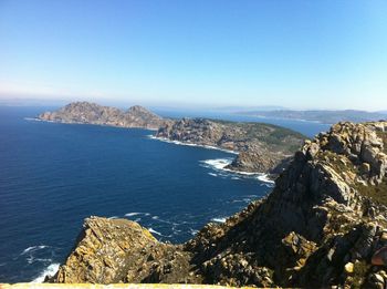 Scenic view of sea and mountains against clear blue sky