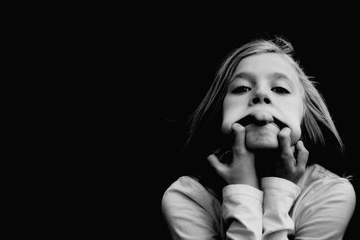 Portrait of cute girl against black background