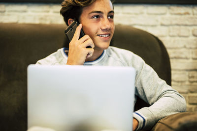 Teenage boy talking on phone at home