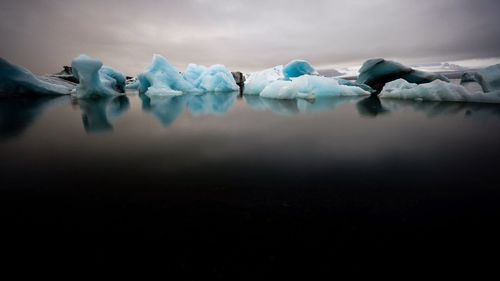 Ice floating on water against sky during winter