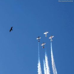 Low angle view of airplane flying against clear blue sky