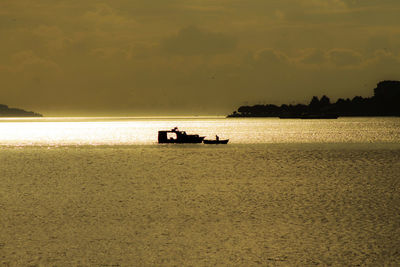 Silhouette boat on sea against sky during sunset