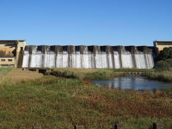 Built structure by water against clear sky