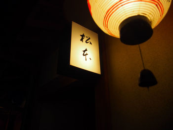 Close-up of illuminated lamp hanging against wall at home