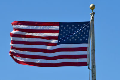 Low angle view of american flag against clear blue sky