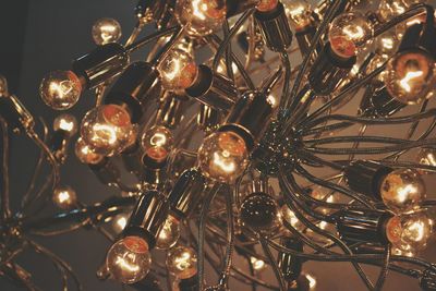 Low angle view of illuminated light bulbs hanging at night