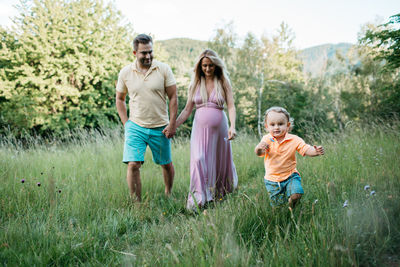 Pregnant woman with family walking on field at park