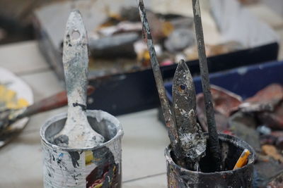 Close-up of messy painting equipment on table at workshop