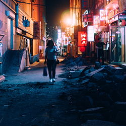 Full length of woman walking on footpath in market at night