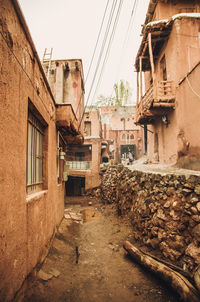 Alley amidst old houses in town against clear sky